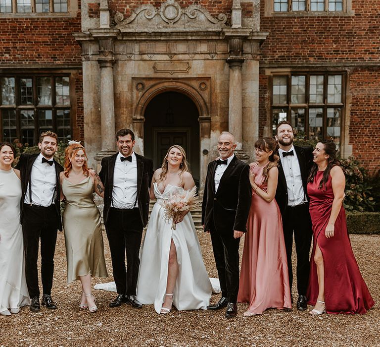 Wedding party in black velvet tuxedos with the bridesmaids in satin mismatched bridesmaid dresses for the country house wedding 