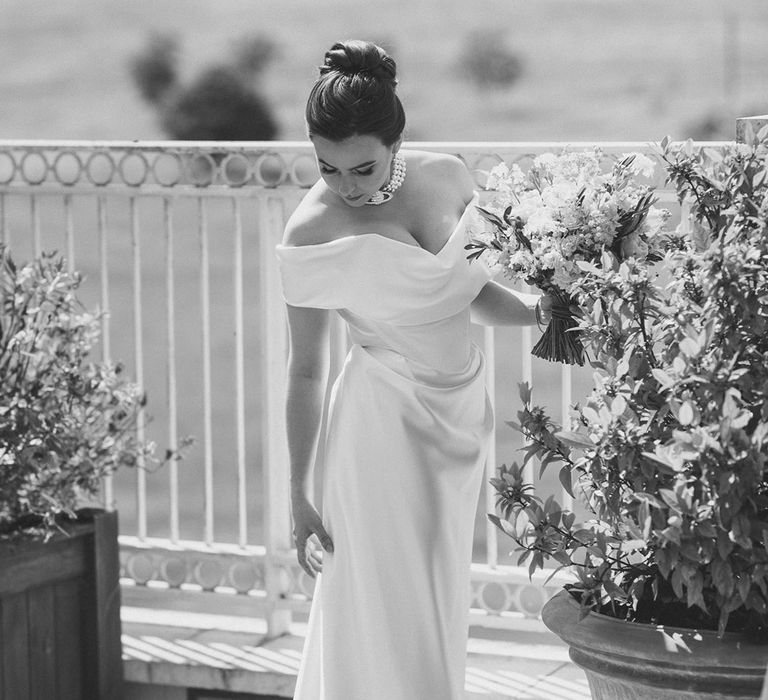 Bride in elegant off the shoulder wedding dress by Vivienne Westwood with pearl choker necklace 