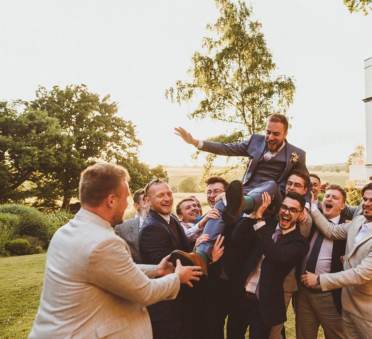 Groomsmen lift up the groom to celebrate the wedding 