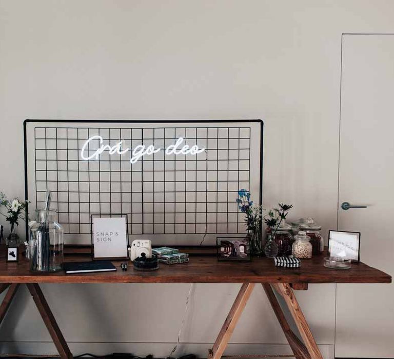 Back grid mesh panel with white neon wedding sign, alternative wedding guest book and delicate white and blue flower arrangements 