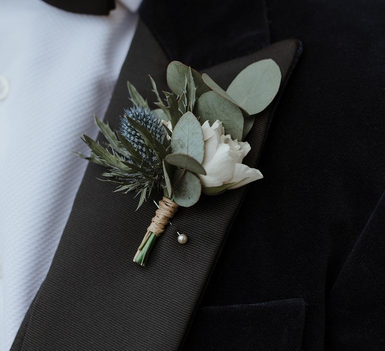 Groom in black tuxedo with traditional white flower buttonhole for wedding 