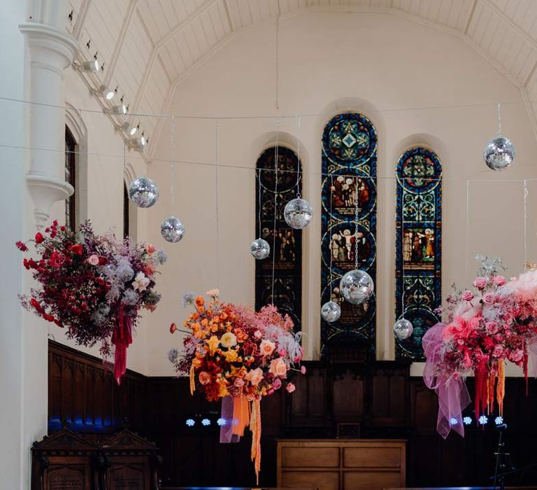 Fabrica Brighton wedding venue with suspended colourful flower arrangements and suspended disco ball wedding decor 