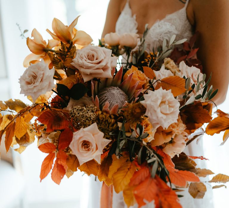 Pale pink roses and king proteas with autumn leaves in wedding bouquet for autumn theme wedding 