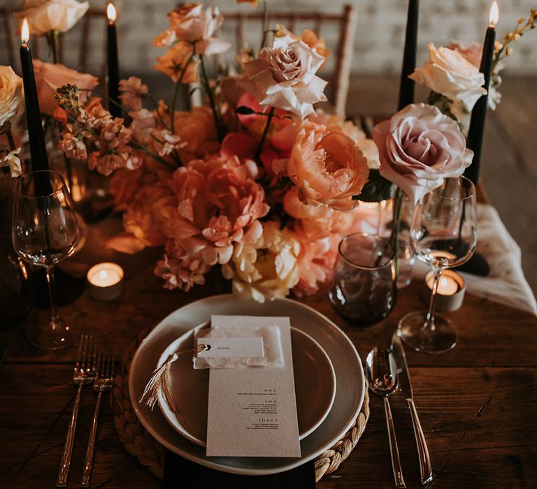 Speckled wedding plates with pink and neutral wedding flower arrangements with black accent candles 