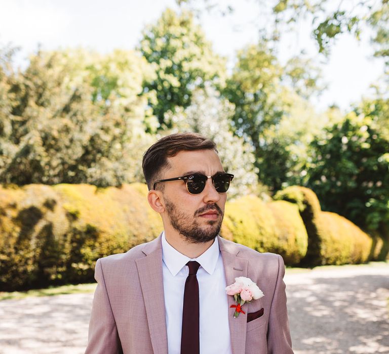 Groom in taupe suit with black sunglasses with burgundy tie 