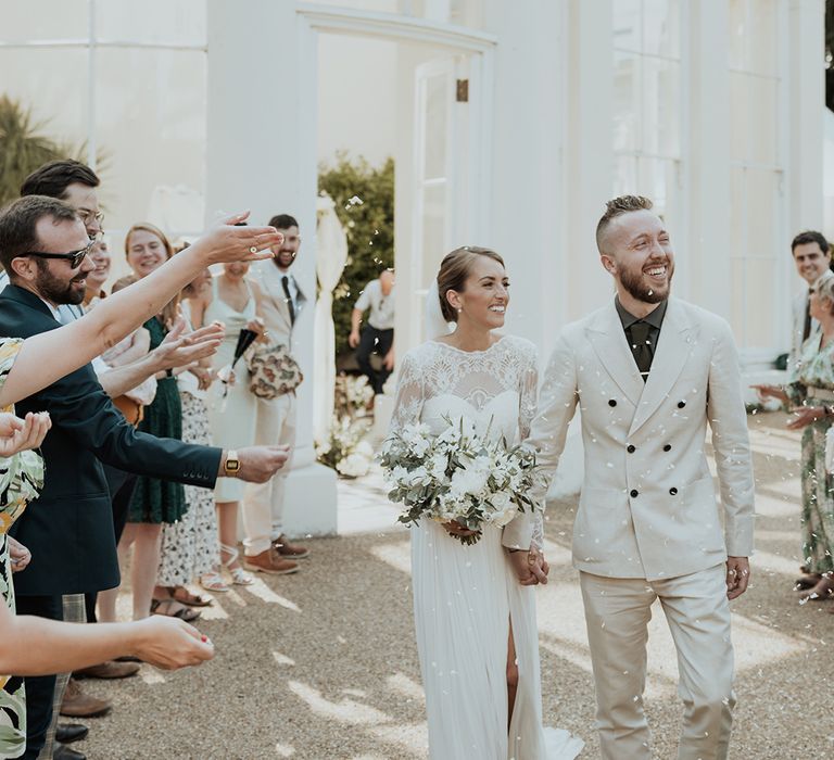 confetti moment outside Gunnersbury wedding venue with beige wedding suit and Catherine Deane wedding dress