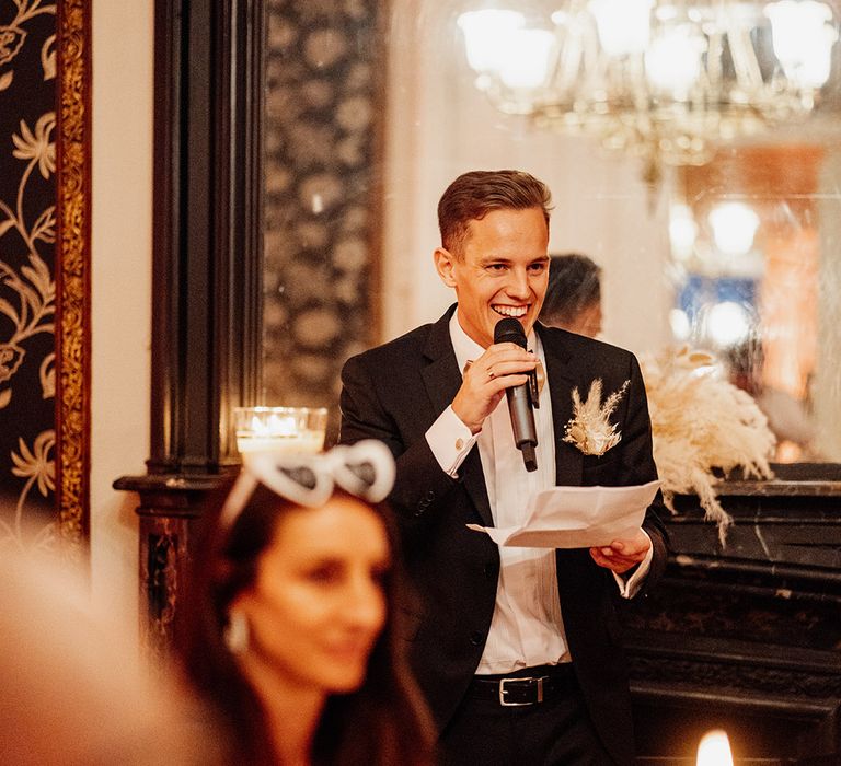 Groom with microphone reading wedding speech at the wedding 