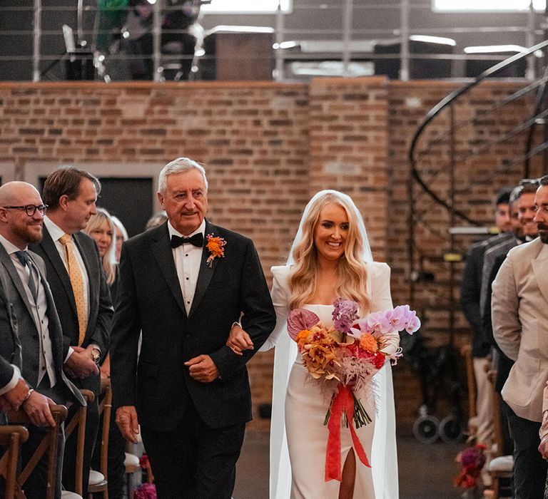 Father of the bride in a black tux walking the bride down the aisle 