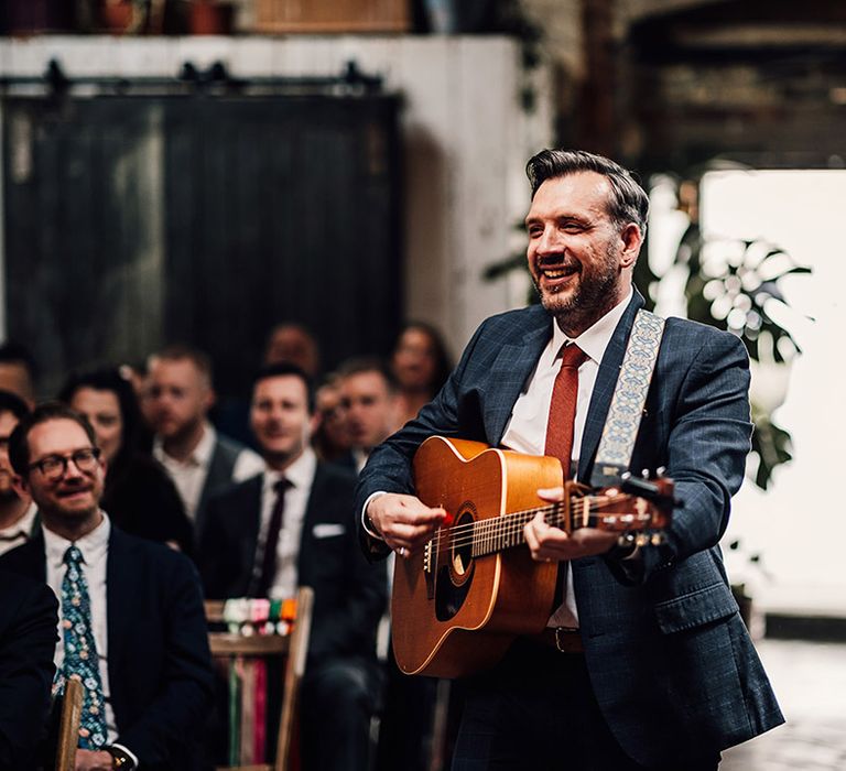 The master of ceremonies performs a song on the guitar walking down the aisle 