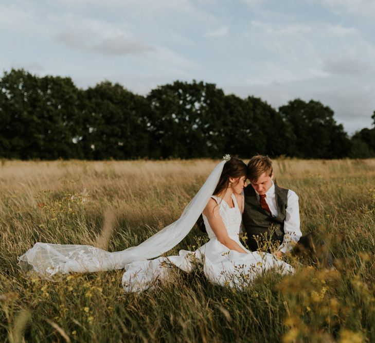 Bride and groom portrait sitting in a field 