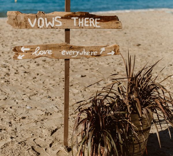 Beach wedding signage that says 'Shoes here, vows there, love everywhere'