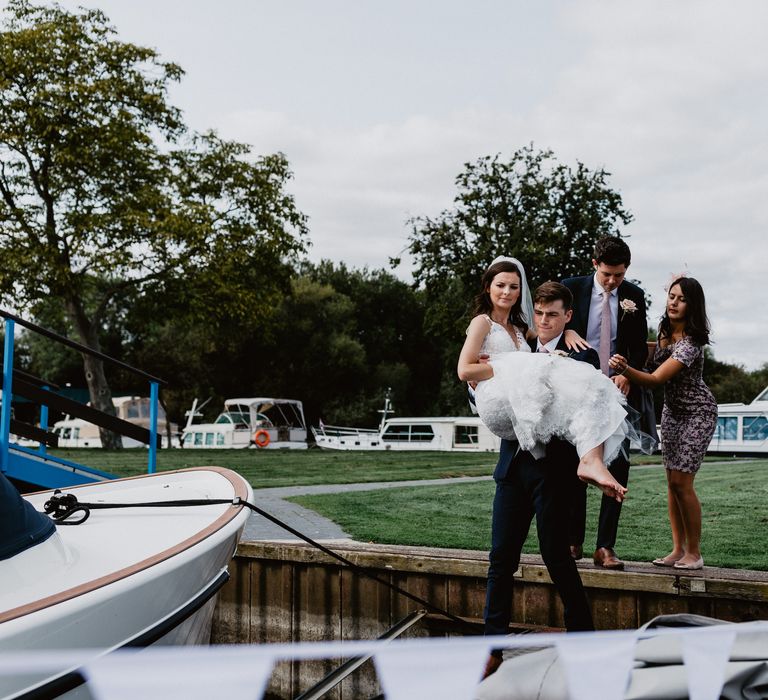 Groom lifts bride on to boat at wedding reception 