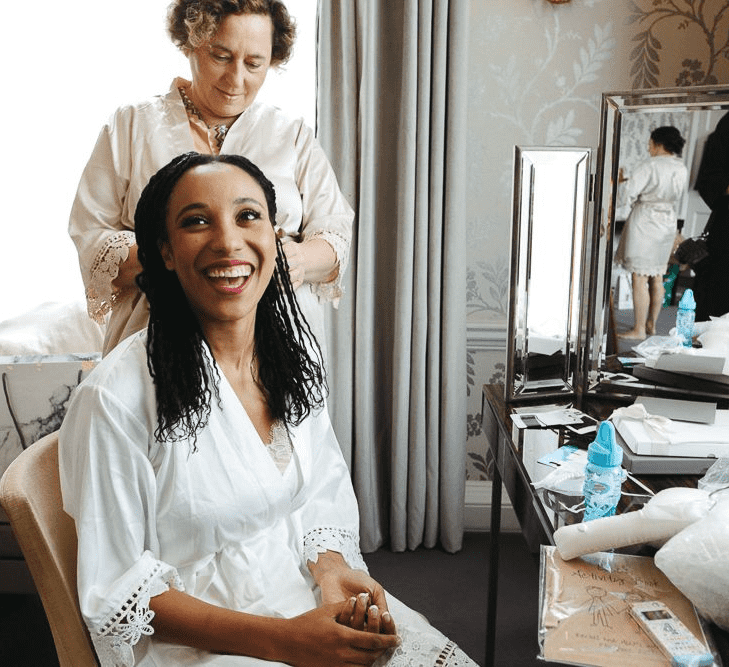 A bride laughs as she has her hair twisted before her wedding ceremony