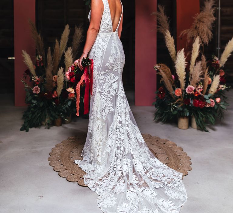 Bride stands in front of floral bouquets with pampas grass