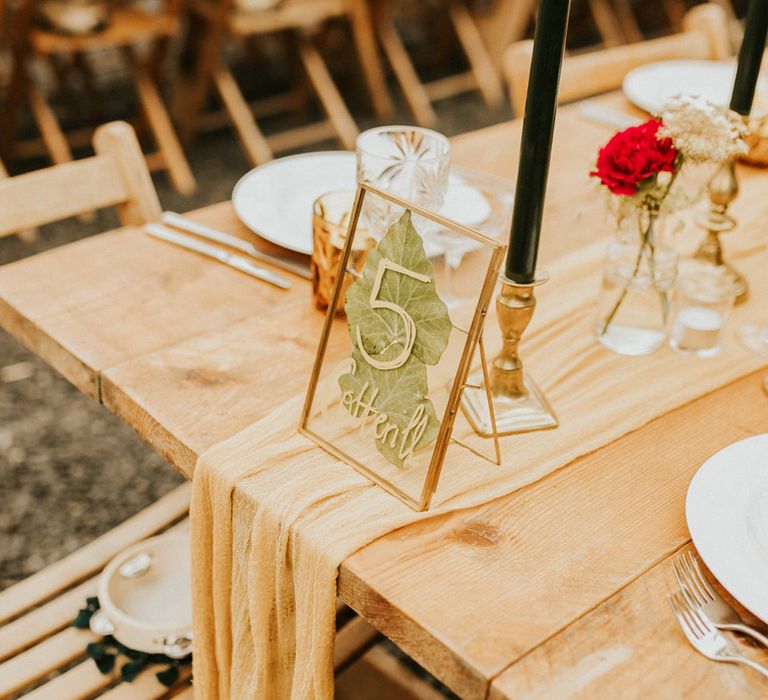 fabric table runner and table name in a gold frame with no back 