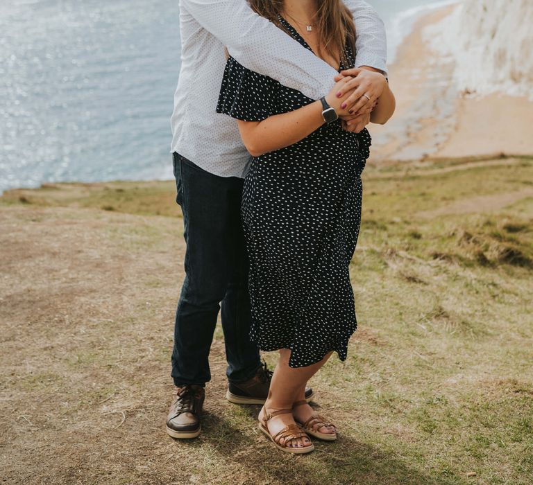 Couple hugging each other for engagement shoot at Durdle Door in Dorset