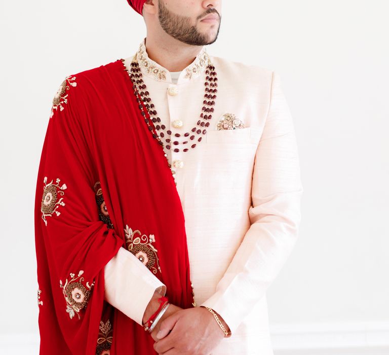 Groom wears red and pale pink suit with stone embellishment 