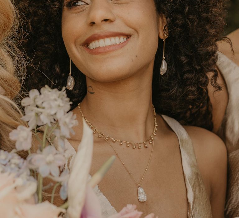 Beautiful black bridesmaid with naturally curly hair wearing dangling earrings 