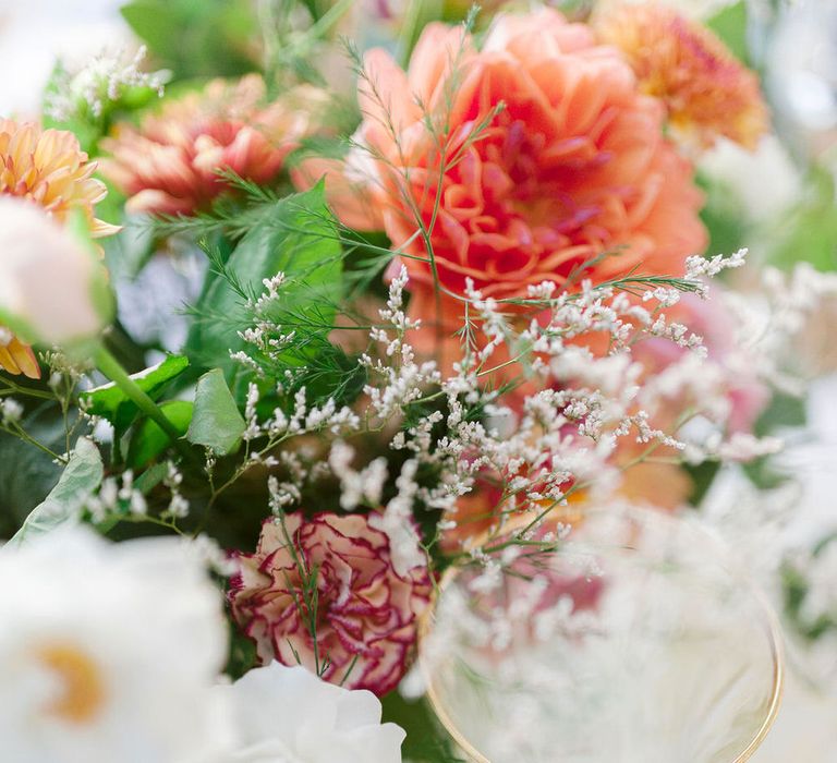 Close up details of the table centrepieces with carnations, wildflowers and gold rimmed glassware