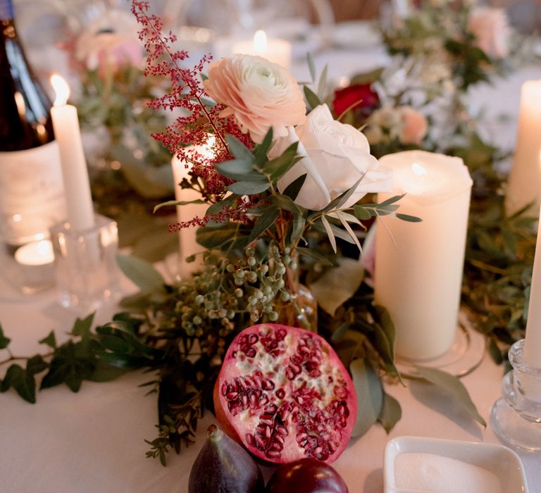 Wedding table décor with red flowers, plums and pomegranate 