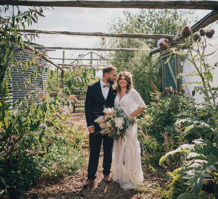 Bride & groom pose under pergola after wedding ceremony