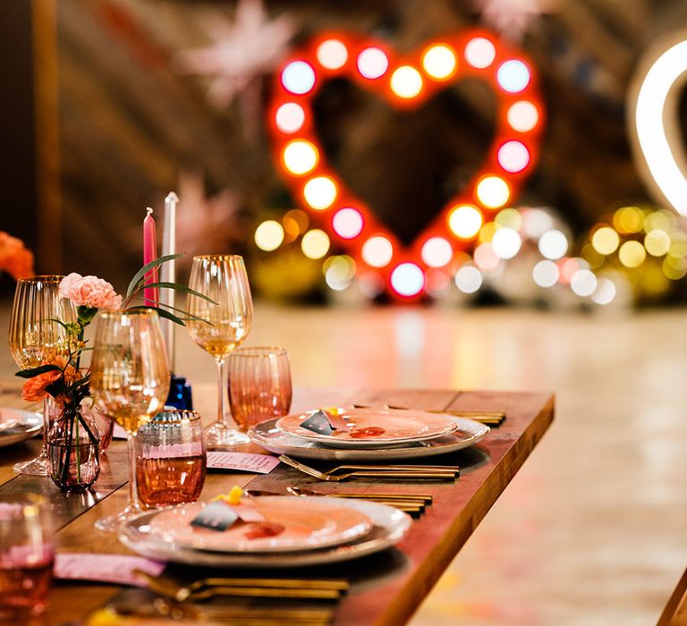 Coloured glassware wedding reception decor glistening in under the neon wedding sign lights 