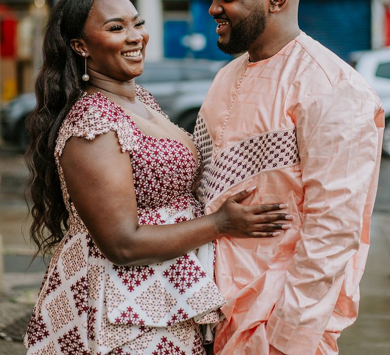 Bride & groom wear traditional Senegalese outfits in colourful prints on their wedding day outdoors 