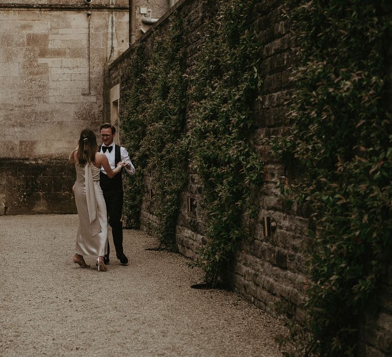 Brie & groom walk together whilst wearing reception outfits on the day of their wedding