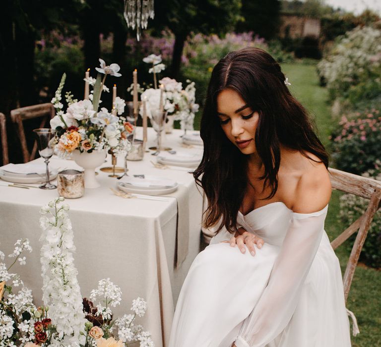 Bride in a chiffon wedding dress adjusting the straps on her diamanté peep toe wedding shoes 