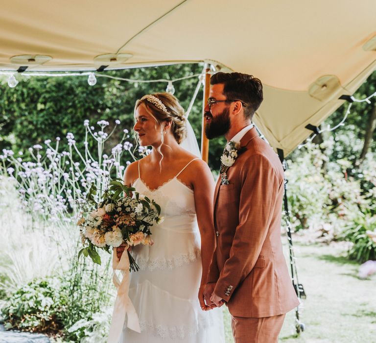 Bride & groom smile as they marry under tipi on a bright & sunny day in Cornwall 