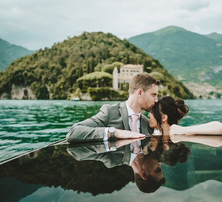 Bride & groom kiss as Lake Como can be seen in the background glistening in the sunlight