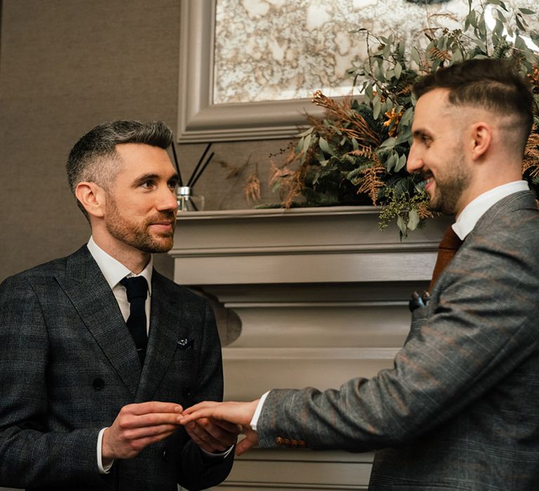 Grooms look lovingly at one another during wedding ceremony