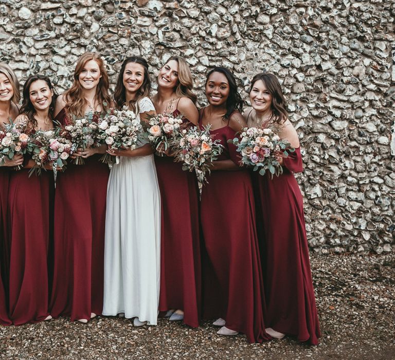 Bride with her six bridesmaids in cold shoulder burgundy ReWritten dresses holding their bouquets