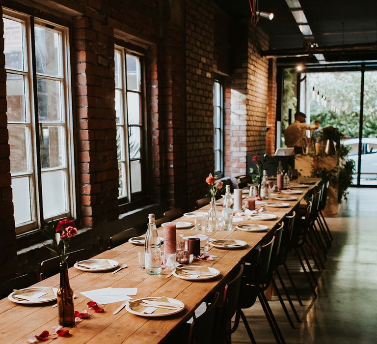 Long wooden trestle tables are laid out for a wedding breakfast at an industrial wedding venue in Sheffield.