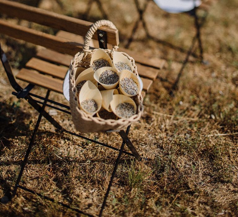 Confetti hangs in wicker baskets on wooden chair outdoors before wedding ceremony