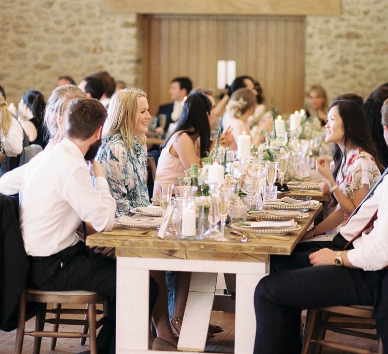 Rustic barn wedding reception with hanging festoon lights and clear glass charger plates 