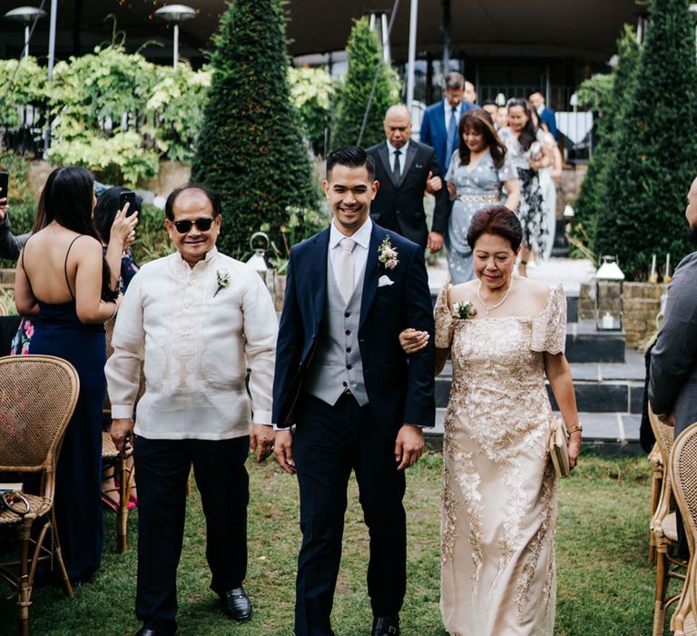 South Asian father with Gold embroidery and mother of the bride in gold feature dress with cheerful Groom