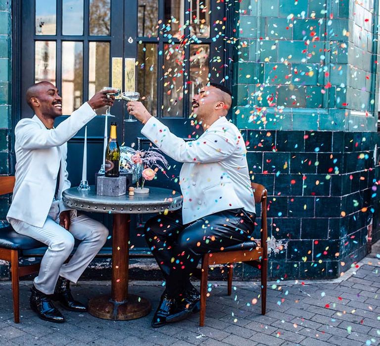 Groom and groom confetti moment whilst they are sipping champagne at their stylish city elopement 