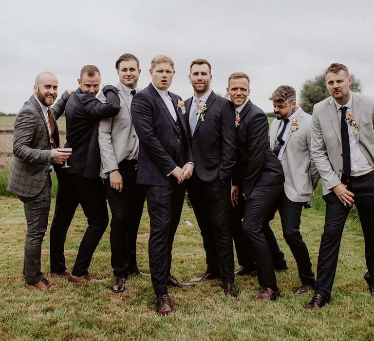 Groom stands with his groomsmen on wedding day