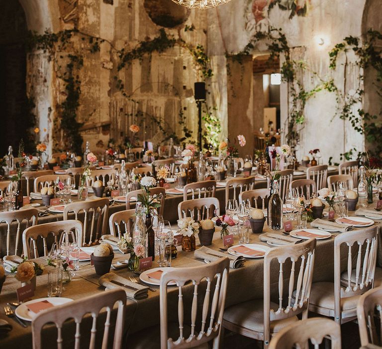 Ball lighting hangs from ceiling alongside vines climbing the walls and rustic tablescapes 