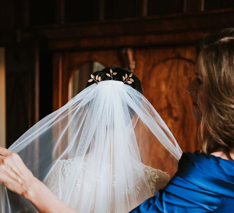 Bride putting on her cathedral length wedding veil 