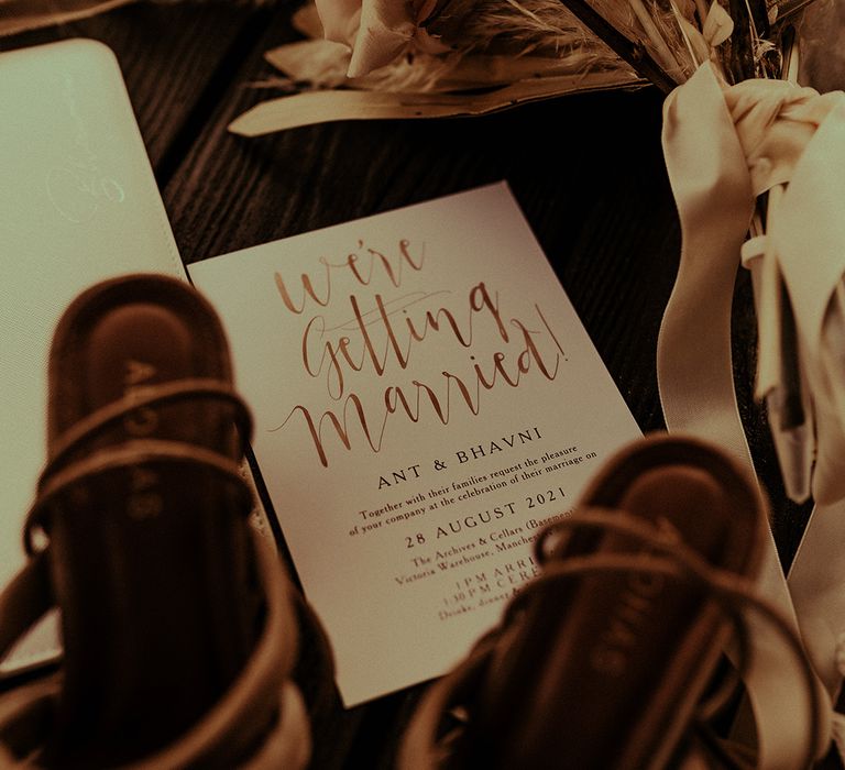 Wedding invitation with gold foil, dried flower bouquet and wedding shoes 