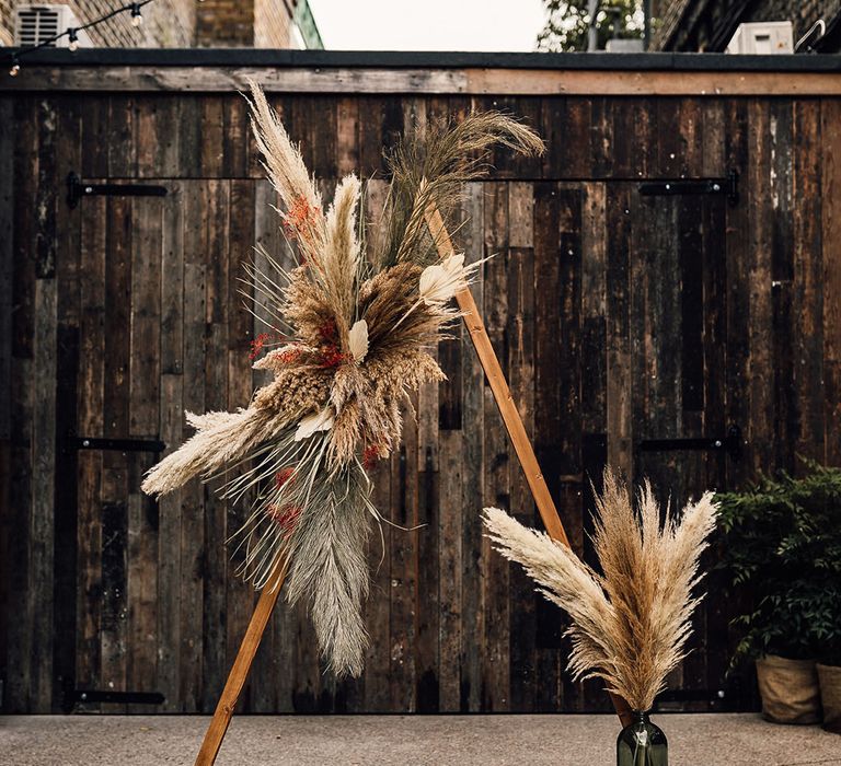 Wooden framed altar decorated with dried pampas grass, palm leaves and foliage 