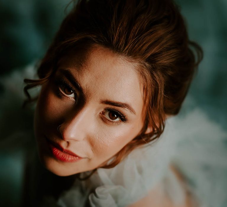 Bride with pinned wedding up do, subtle red lipstick and eye makeup 