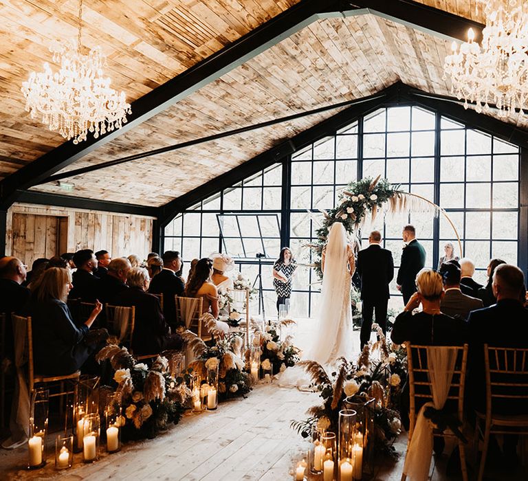 Bride and groom get married at black tie barn wedding venue in winter with chandeliers and moongate