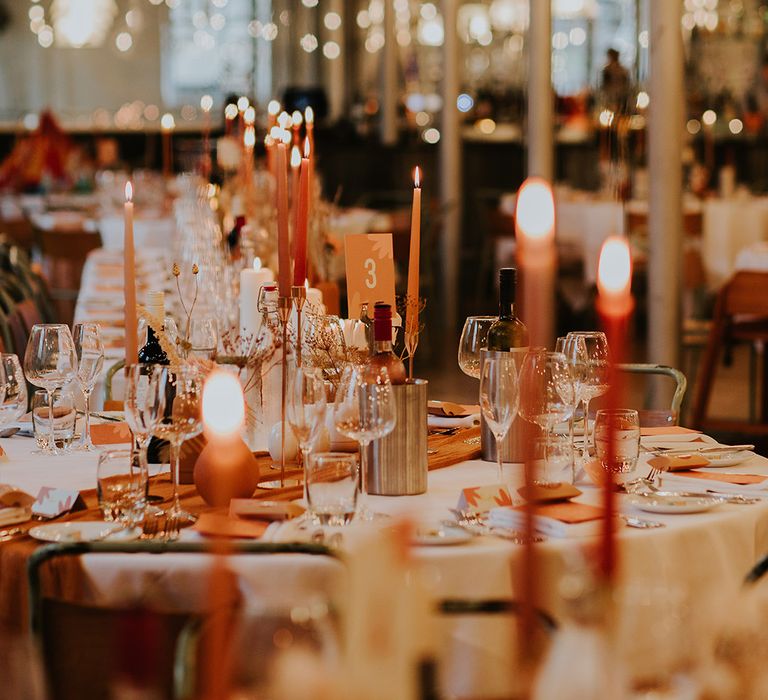 Orange table number sign with flower print and coloured candles and vases to match autumnal theme