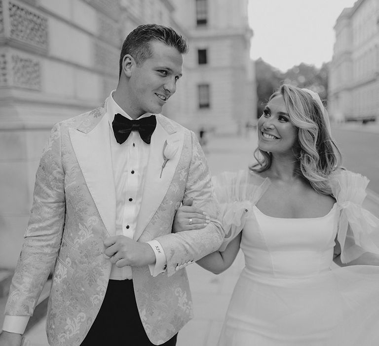 Groom in black tie with white tulip buttonhole and bride in ruffle sleeves wedding dress in London