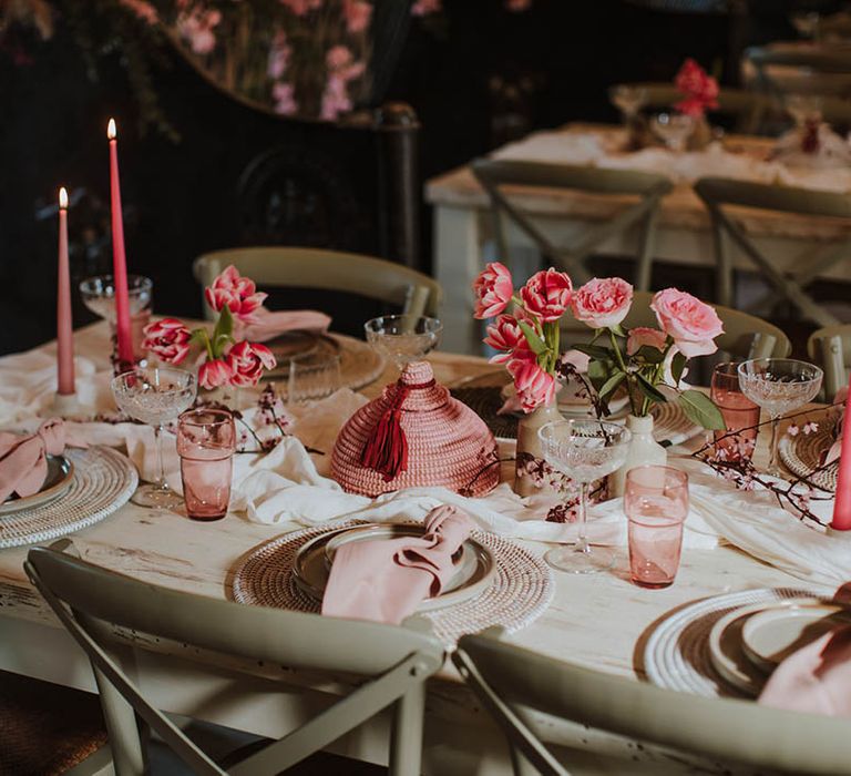 wedding table decor with wicker place mats, pink taper candles and pink floral arrangements 