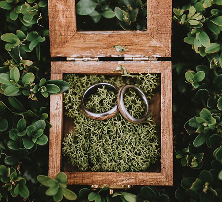 Wooden box with decorative moss with the groom's wood inlaid wedding bands