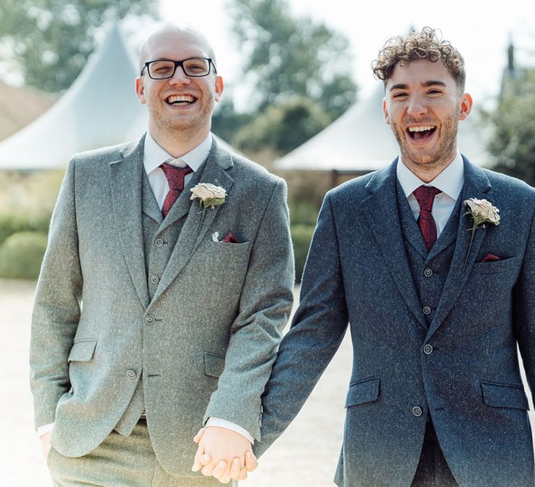 Grooms in grey and blue three piece suits with red ties and paper rose boutonnière made from pages of their favourite books